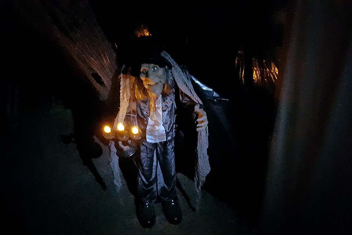 A scary hunchbacked man coming out of the shadow, holding a candelabrum